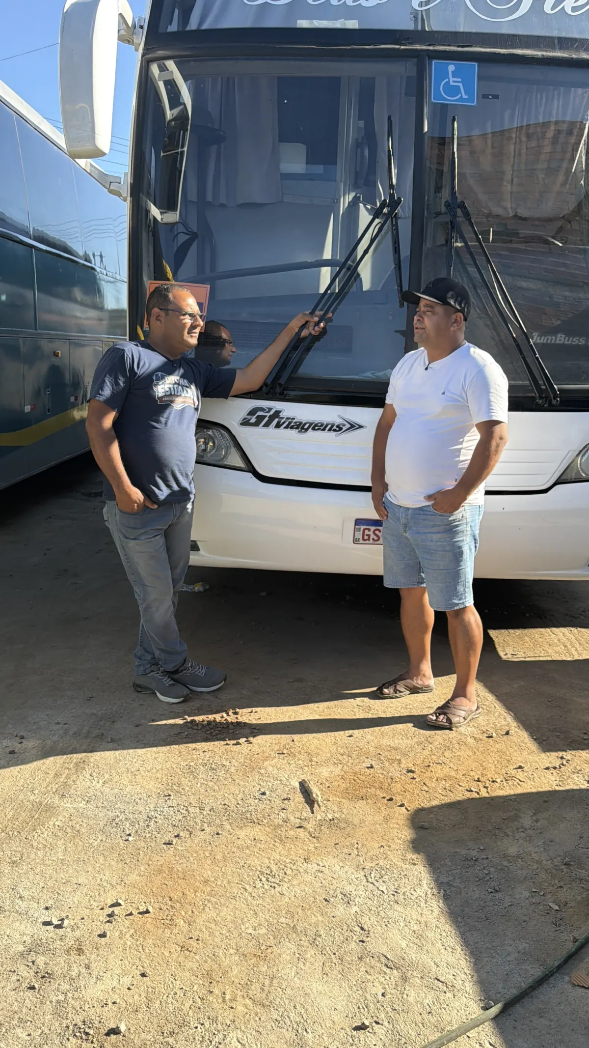 Dito ouvindo um trabalhador do transporte em frente a um ônibus